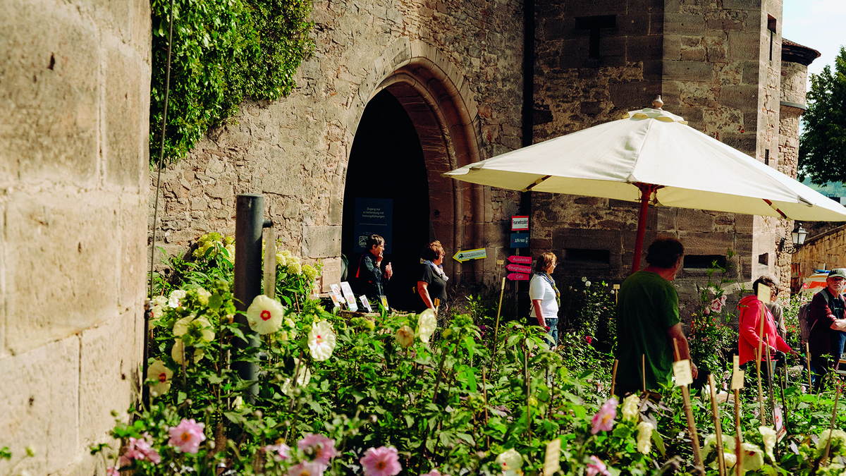 Tor der Festung Rosenberg mit Blumen und Wegweisern